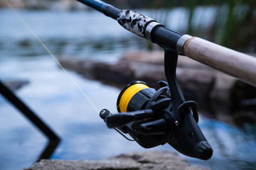 Outdoor shot of modern feeder fishing reel in black color - 310432570