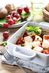 Baked feta cheese with cherry tomatoes with basil and olive oil. Greek national cuisine.