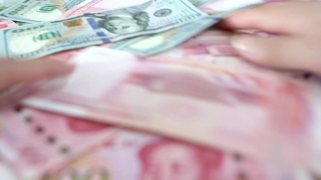 Chinese and American paper money, close up hands stirs shuffles cash money on the table, concept idea and blur view