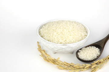 Fototapeta na wymiar Japanese rice in ceramic cups and wooden spoons and grains of rice on isolated white background.