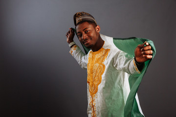 Young man in yoruba and national clothes holding Nigeria Flag in gray Background, Flag of Nigeria.
