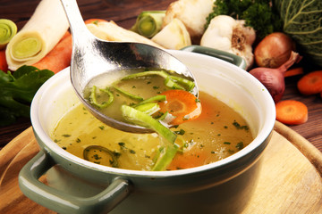Broth with carrots, onions various fresh vegetables in a pot - colorful fresh clear spring soup....