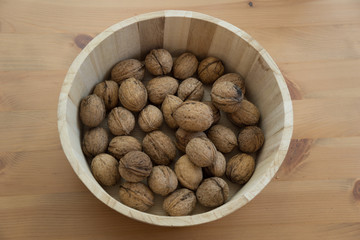 Basket with tasty walnuts on wooden background