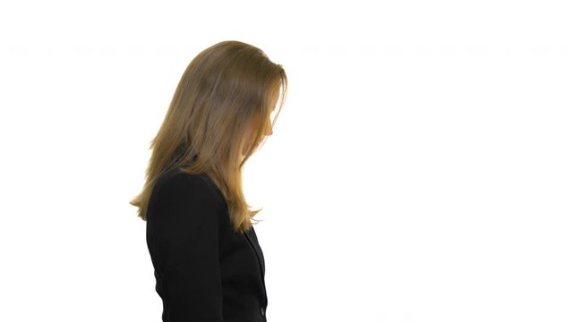 A side profile of a woman wearing a black blazer jacket, tilting her head back on a seamless white studio background