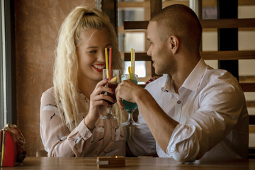 Young african man and blonde american woman drink cocktail, happy couple in bar drink cocktail and have fun
