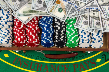 Gambling concept. Colorful poker chips with american dollars in wooden box on green playing table.