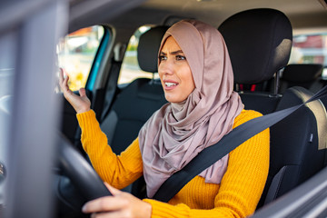 Stressed Muslim woman drive car feeling sad and angry. Distraught mid adult woman driving a car. Displeased young stressed angry pissed off woman driving car annoyed by heavy traffic