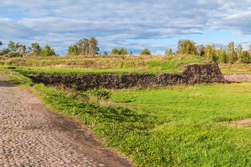 Fototapeta na wymiar Stone walls and moats covered by the grass in Annenkrone in sunny day, Vyborg, Leningrad Oblast, Russia