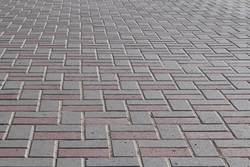 The surface of the pavement paved with paving stones of rectangular shape. The pavers are lined with a pattern. Tiles are gray and brown. Background or backdrop.