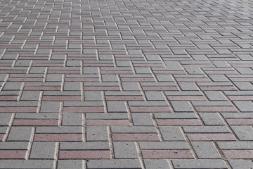 The surface of the pavement paved with paving stones of rectangular shape. The pavers are lined...