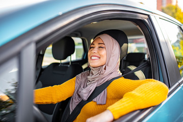 Young asian muslim woman in head scarf smile inside the car. Beautiful caucasian Muslim Woman wearing light hijab in a car lifestyle shoot. Beautiful muslim woman with toothy smile driving car.