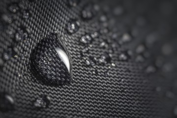 Water drop on waterproof impregnated fabric of black umbrella during rain.
