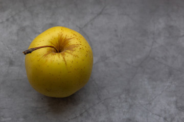 Top view of yellow apple on grey stone table