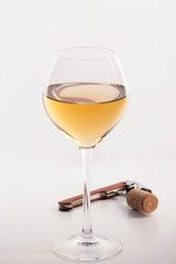 View with shallow depth of field of a glass of white wine with a sommelier tools.