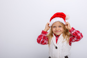 cute happy little girl in santa claus hat. Santa's assistant smiles on a white background