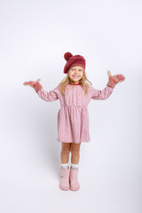 cute happy little girl in mittens, gloves and a winter hat on a white background in full growth