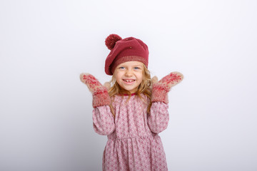 cute happy little girl in mittens, gloves and a winter hat on a white background