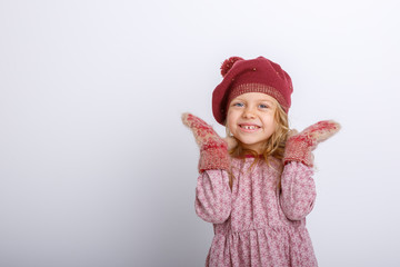 cute happy little girl in mittens, gloves and a winter hat on a white background