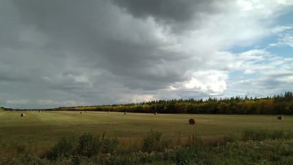 Fototapeta na wymiar sun and clouds over the harvest field near Ilek