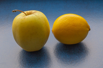 Yellow apple and lemon on blue table