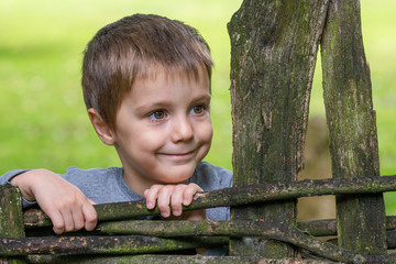 portrait of little boy leaned on wooden fence