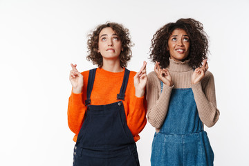 Portrait of multinational women looking upward with fingers crossed
