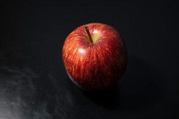 Red apples placed on a black leather floor
