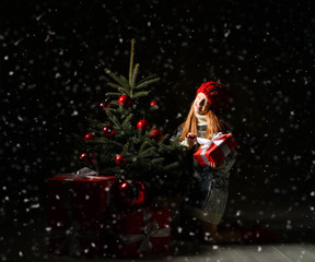 Young teen girl celebrating New year 2020 Xmas and decorates a christmas tree in red winter hat and presents gift boxes