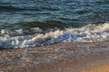 splashes of waves on the beach of the sea coast at sunset