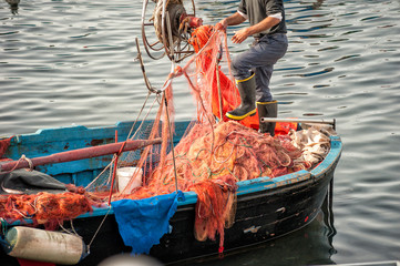Fisherman working on fishing nets in the port of pozzuoli, naples, italy. - obrazy, fototapety, plakaty