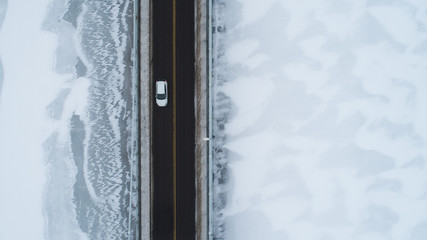 Aerial view of straight winter road. Drone captured shot from above. Highway in Finland. White car...