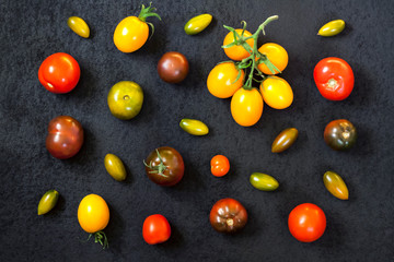 Assortment of colorful fresh tomatoes on black background