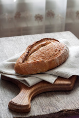 Loaf of whole wheat bread wooden board on kitchen table