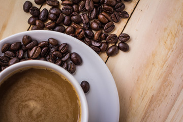Cup of coffee, roasted coffee beans on the table.