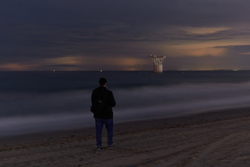 Fototapeta premium Man looking at mine tower from beach