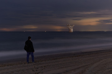 Man looking at mine tower from beach