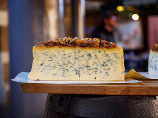 Wide closeup of a Stilton blue cheese wheel topped with walnuts cut in half and sold at an open market. Shallow focus. London, United Kingdom. travel and cuisine. - 310449536