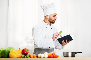 Chef Man Reading Culinary Recipe Book Preparing Dinner In Kitchen