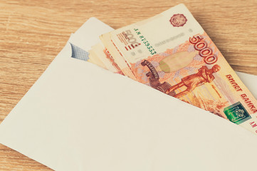 Envelope with ruble bills. Bribe. A stack of large ruble notes protrudes from a white envelope.