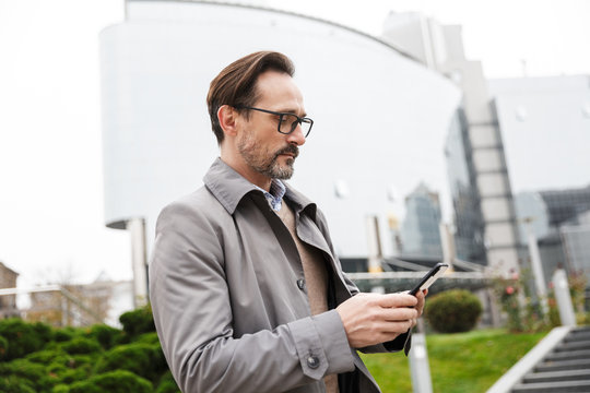 Image of handsome focused businessman using cellphone