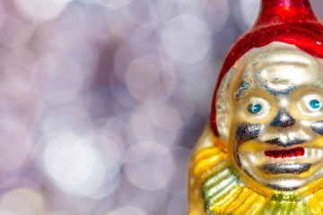 Vintage decorative christmas bauble in a shape of a crown jester against a colorful bokeh blury star background.