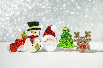 Happy Christmas card background idea, decoration item, Snowman and Santa with shiny green Christmas tree and reindeer over blurred silver bokeh background