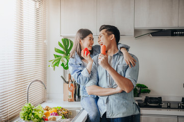 couple in love smiling and having fun with vegetables in kitchen