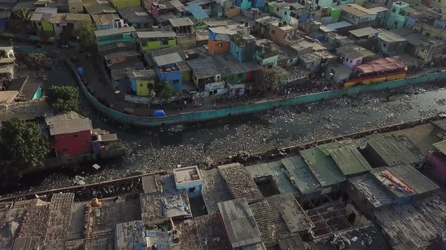 Tilt Up Aerial View on Dharavi Slum With Dirty Water Canal and Overview on Mumbai Downtown Skyline