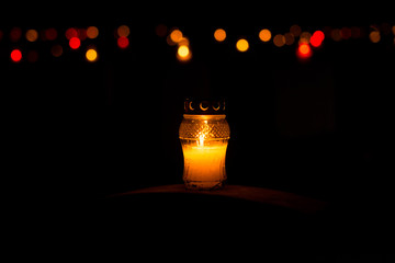 Candle snitch on the tombstone, the feast of the dead, All Saints' Day by night with bokeh colorful background. Copy space