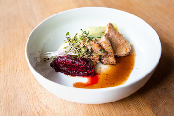 Delicious roasted pork filet cooked with smashed potatoes and smashed beetroots served in white plate.