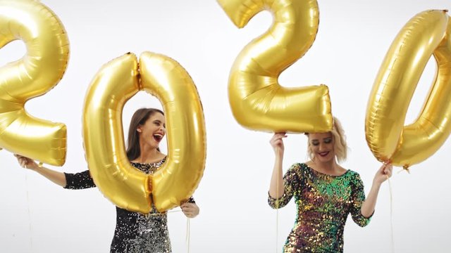 Women with golden balloons building the figure "2020”