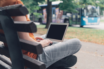 Woman using laptop computer on street bench, mock up screen