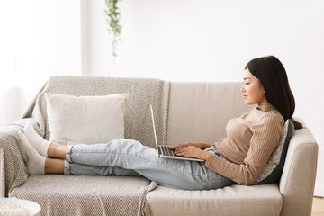 Lazy weekend. Young girl relaxing on sofa with laptop