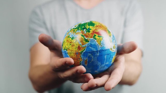 World Environment Day.  Global warming and plastic emissions. Male hand holds planet earth ball. The globe with geographical names in Ukrainian cyrillic. Letters on it in polyethylene. Zero waste